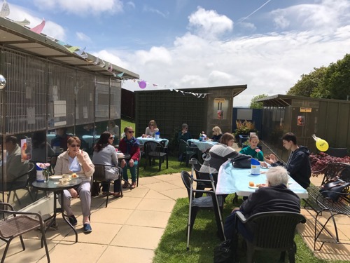 Courtyard with people sitting at tables eating cake on a sunny day