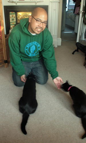 man sitting with two black cats