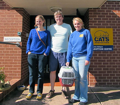 woman in Cats Protection jumper holding cat carrier next to couple