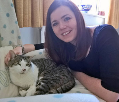 Women with long brown hair stroking a white-and-grey tabby cat