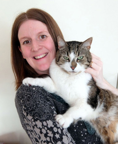 brown-haired woman holding tabby and white cat