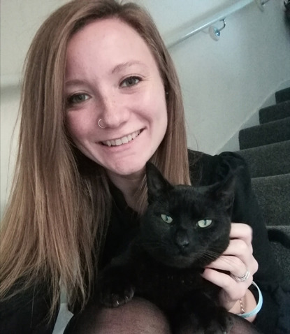 long-haired brunette woman with black cat on lap