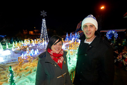 man and woman standing in front of big Christmas light display