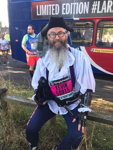 man with long-grey beard wearing pirate hat and white frilly pirate shirt and holding toy black bird